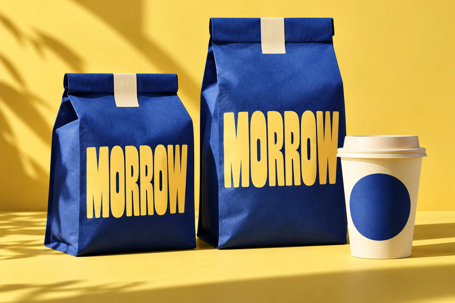 Cobalt blue Morrow coffee packaging and a cream cup on a yellow background